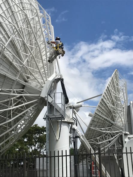 A USSI Global field engineer performing maintenance on a satellite dish at a customer facility in Miami, Florida.